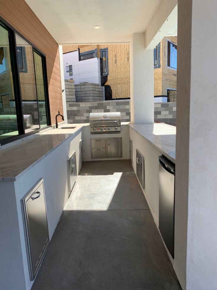 Cocina exterior en L con gabinetes y countertop de granito