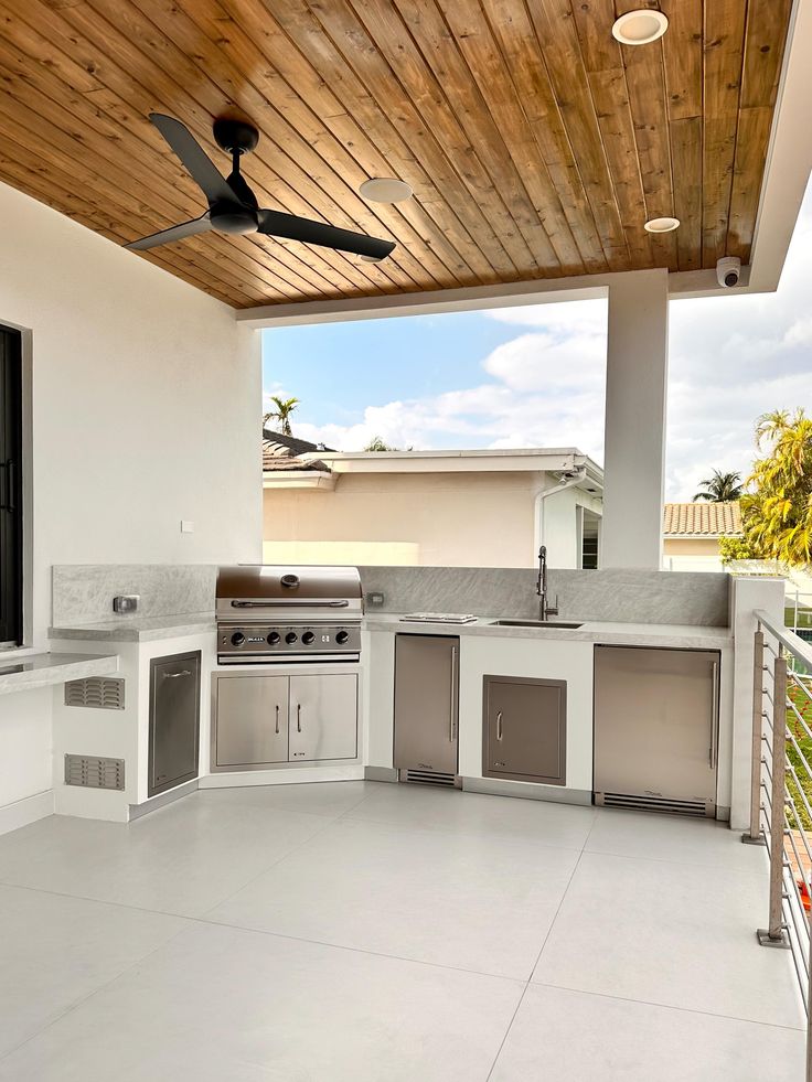 Cocina exterior moderna blanca bajo techo de madera con abanico